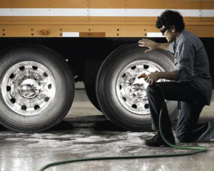 Image of man kneeling by truck wheels