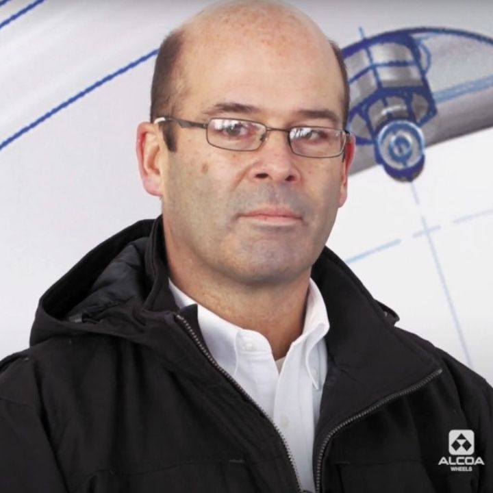 Doug Mason, Alcoa Wheels Global Technology Manager against a technical drawing background of an Alcoa Wheel