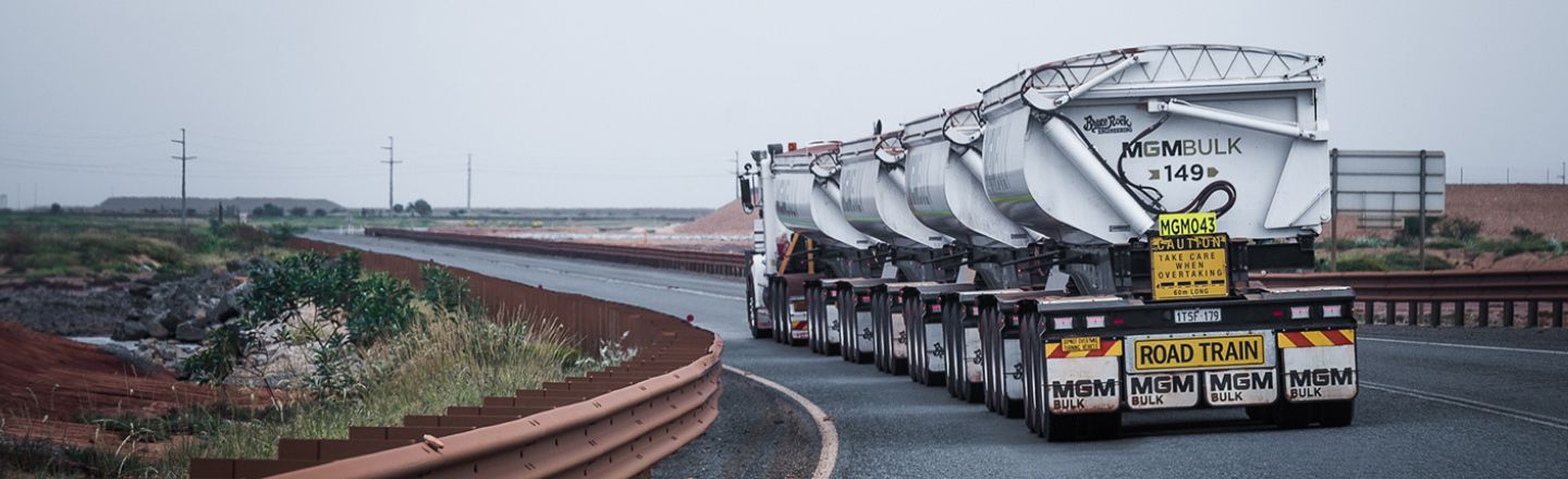 A long white MGM Bulk road train on Alcoa Wheels travelling along an empty road